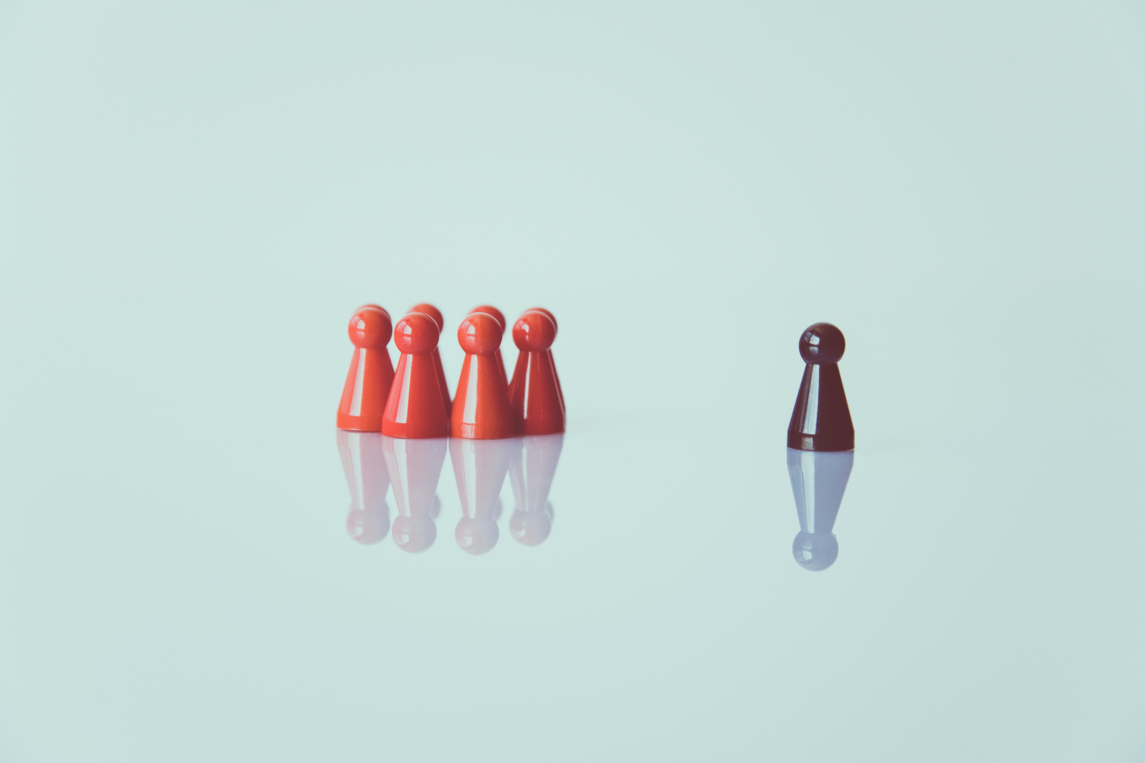 Lone pawn looking at group of red pawns